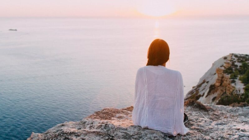 ragazza su una roccia che guarda il mare