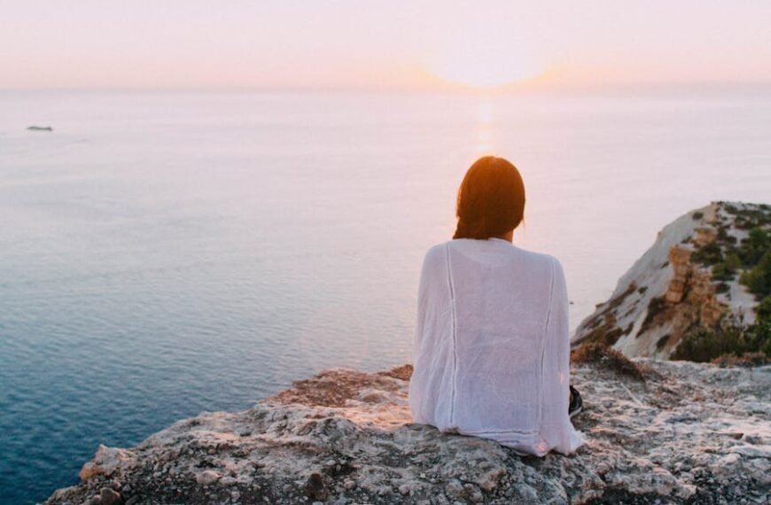 ragazza su una roccia che guarda il mare